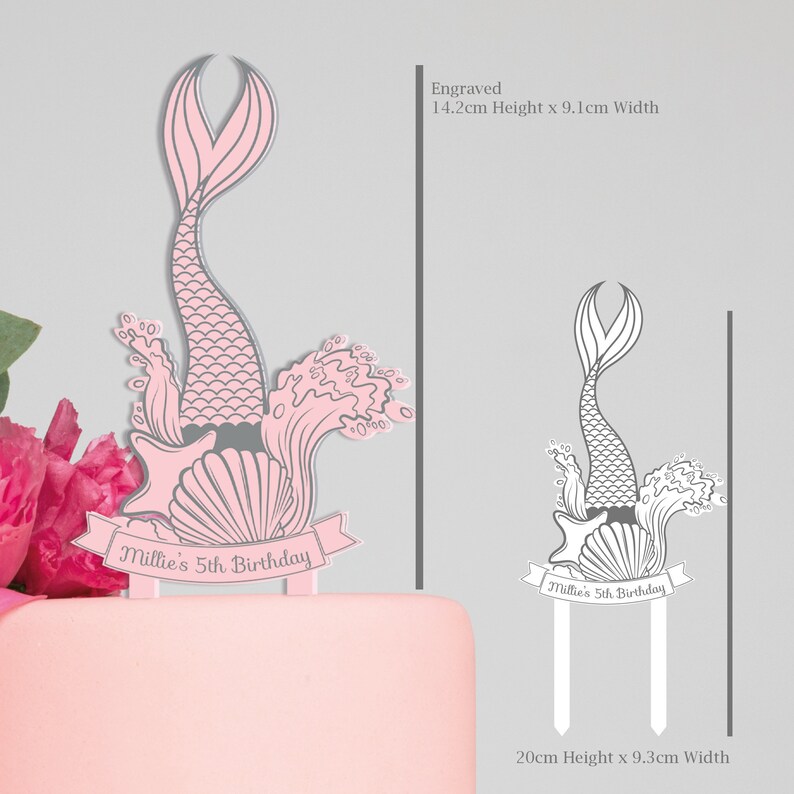 May include: Pink and gray mermaid cake topper with a shell, starfish, and waves. The topper is 14.2 inches tall and 9.1 inches wide. The topper says "Millie's 5th Birthday".