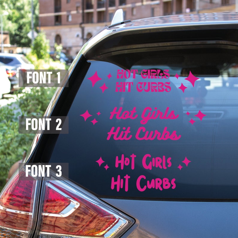 May include: A pink car window sticker with the text "Hot Girls Hit Curbs" in three different fonts. The sticker is decorated with small pink stars.