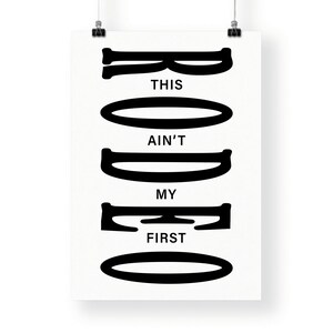 May include: Black and white graphic print with the text "This ain't my first rodeo" in a stylized font.