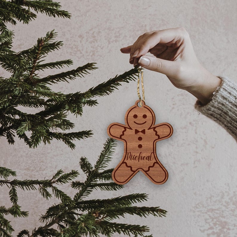 Puede incluir: Un adorno navide&ntilde;o de madera en forma de hombre de jengibre con una corbata de mo&ntilde;o y el nombre "Michael" grabado en &eacute;l.