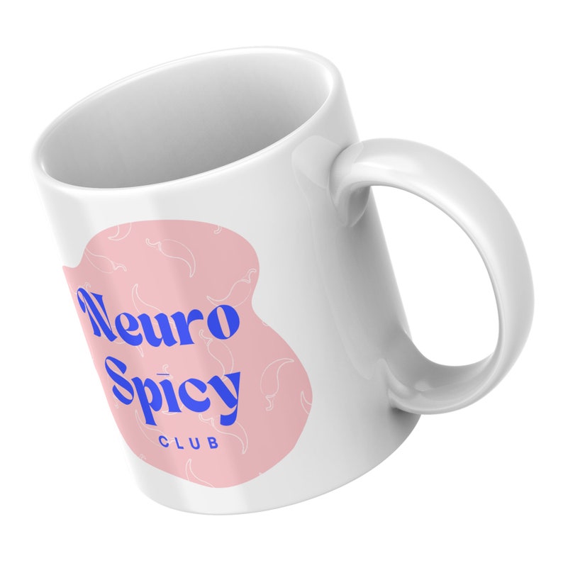 May include: White ceramic mug with a pink and white design. The design features a pink background with white chili peppers and the text "Neuro Spicy Club" in blue.