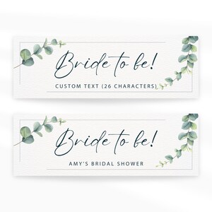 May include: Two rectangular cards with the text "Bride to be!" in elegant script. The cards are decorated with watercolor eucalyptus leaves and the text "CUSTOM TEXT (26 CHARACTERS)" and "AMY'S BRIDAL SHOWER".