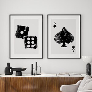 May include: Two black and white framed prints, one with a stylised image of dice and the other with a stylised image of the ace of spades.