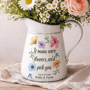 May include: White enamel pitcher with a handle, decorated with colorful floral decals and the text "If mums were flowers, we'd pick you". The pitcher is filled with a bouquet of daisies and roses.