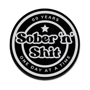 Puede incluir: Pegatina redonda en blanco y negro con el texto "00 YEARS Sober'n Shit ONE DAY AT A TIME" en un c&iacute;rculo blanco con una estrella blanca en el centro.