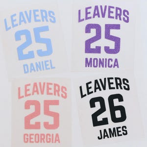 May include: Four personalized iron-on transfers with the word "LEAVERS" above a number and a name. The transfers are in blue, purple, pink, and black. The numbers are 25 and 26. Names include Daniel, Monica, Georgia, and James.