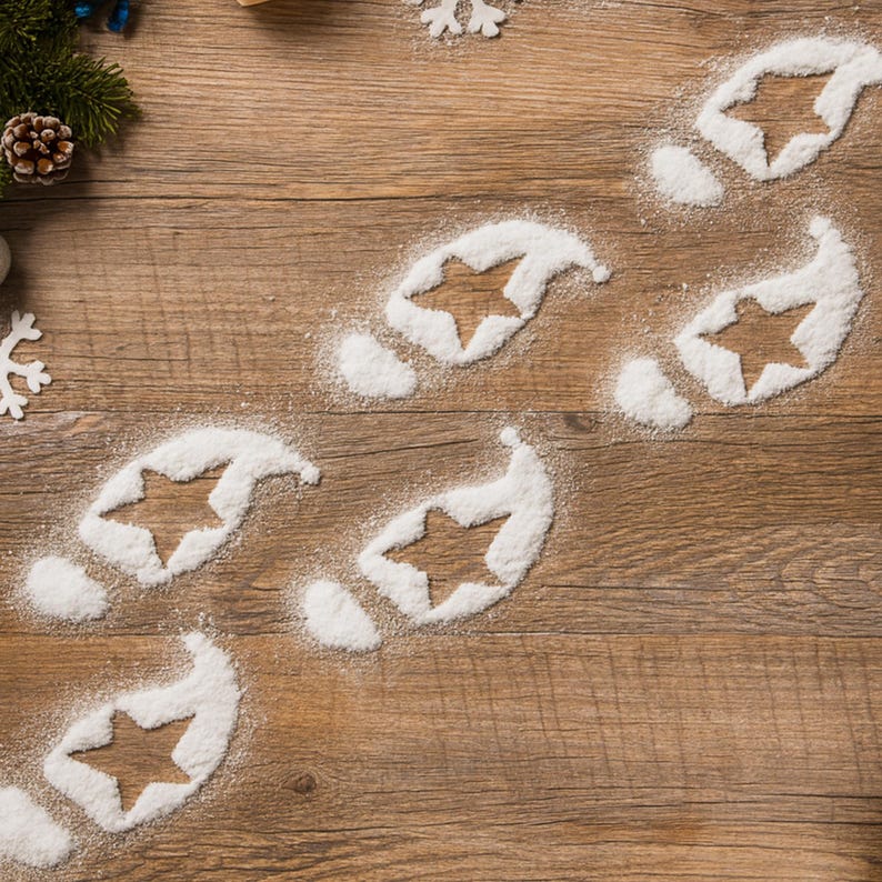 May include: A festive Christmas-themed image featuring a wooden surface with a trail of footprints made of white powder. Each footprint has a star-shaped cutout. Decorative elements like pine needles, a pine cone, and snowflakes are scattered around.