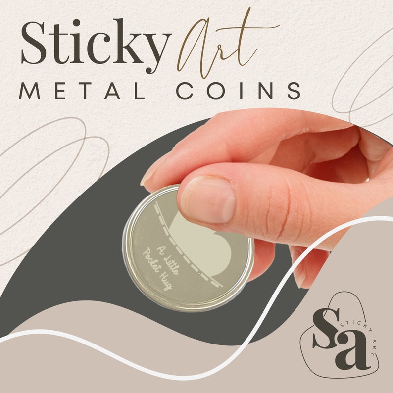 May include: A silver metal coin with the words "A little Pocket Hug" engraved on it. The coin is being held by a hand against a brown and beige background with the words "Sticky Art METAL COINS" at the top.