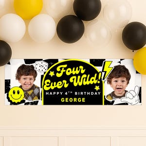 May include: A personalized birthday banner with the text "Four Ever Wild!! Happy 4th Birthday George" in yellow and black. The banner features a photo of a young child, a smiley face, and a dice graphic. Balloons in yellow, white, and black are in the background.