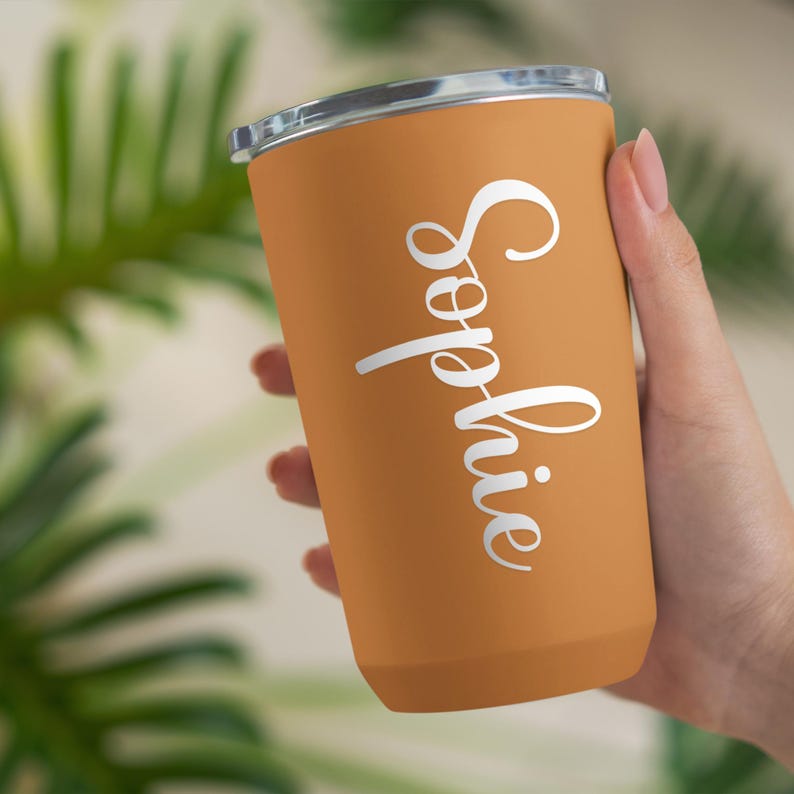 May include: A personalized orange tumbler with a white lid and the name "Sophie" written in cursive on the side.