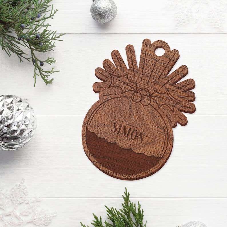 May include: A wooden Christmas ornament shaped like a Christmas pudding with a holly sprig and the name "Simon" engraved on the front.
