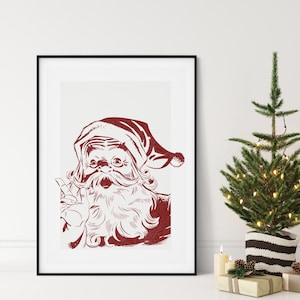 May include: Red and white print of Santa Claus in a black frame. The image shows Santa with a long white beard, a red hat, and glasses, giving a peace sign. The artwork is displayed next to a small Christmas tree.