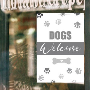 May include: A white sign with gray text and paw prints. The sign reads "DOGS Welcome" with a bone graphic. The sign is displayed on a glass door, with the word "invitation" visible at the top.