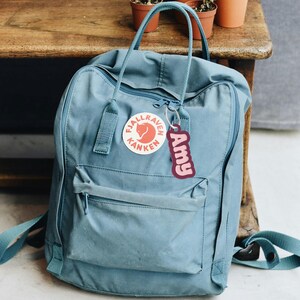 May include: A blue Fj&auml;llr&auml;ven K&aring;nken backpack with a red fox logo and a pink personalized name tag that says "Amy".