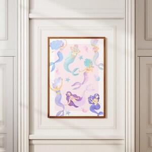May include: A framed print featuring a whimsical illustration of several mermaids in various poses. The mermaids have colorful hair and tails in shades of blue, purple, and teal, set against a soft pink background with stars and bubbles.