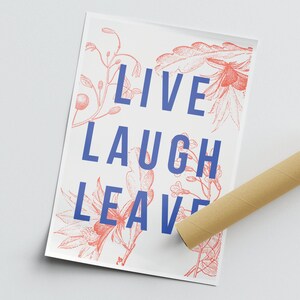 以下が含まれることがあります： ピンクの花柄が描かれた白いポスター。ポスターには「LIVE LAUGH LEAVE」という青い文字が書かれている。