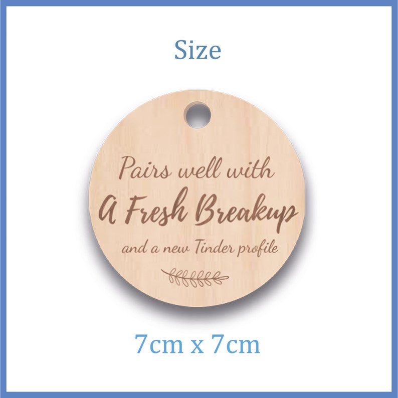 May include: A round wooden tag with a hole at the top. The tag has the text "Pairs well with A Fresh Breakup and a new Tinder profile." The tag measures 7cm x 7cm.