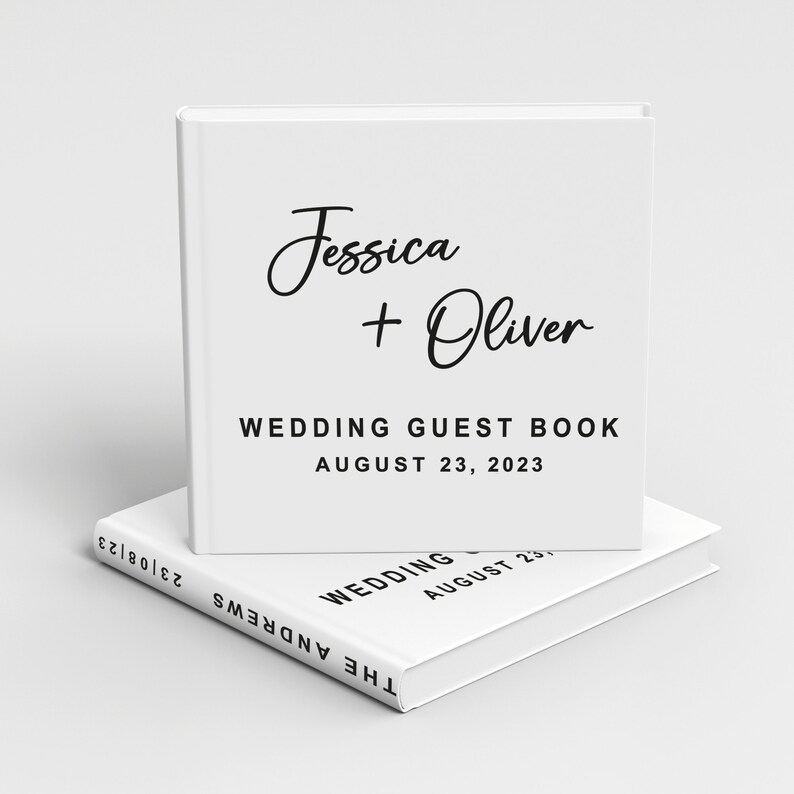 May include: White wedding guest book with the text "Jessica + Oliver" and "Wedding Guest Book August 23, 2023".