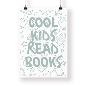 May include: A white poster with the text "COOL KIDS READ BOOKS" in light blue. The background features a pattern of sketched books, tablets, and stars. The poster is held by two black binder clips.