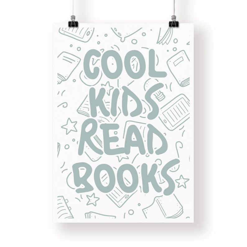 May include: A white poster with the text "COOL KIDS READ BOOKS" in light blue. The background features a pattern of sketched books, tablets, and stars. The poster is held by two black binder clips.