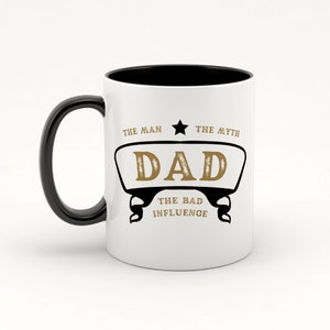 May include: White ceramic mug with a black handle and black interior. The mug has a gold design that says "The Man, The Myth, Dad, The Bad Influence".