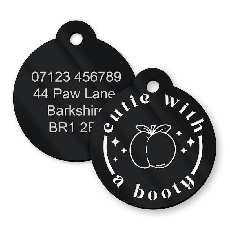May include: Black pet tag featuring the phrase "cutie with a booty" and a peach graphic. The tag also displays a phone number and address in white text.