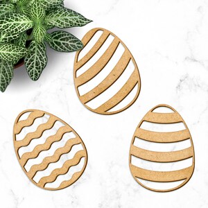 May include: Three wooden Easter eggs with different patterns. One egg has a wavy line pattern, one has a striped pattern, and one has a diagonal striped pattern.