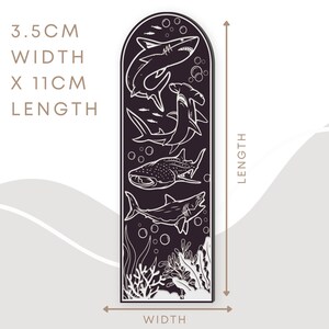 May include: A black and white illustration of four different sharks and a coral reef on a dark purple background. The image measures 3.5 inches wide by 11 inches long.