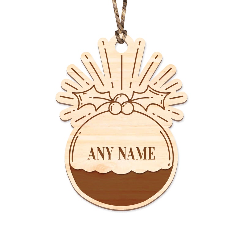 May include: A wooden Christmas ornament shaped like a Christmas pudding with a holly sprig and berries on top. The ornament has a space for a name to be engraved, and the text "ANY NAME" is shown as an example.