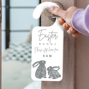 May include: White door hanger with a gray bunny rabbit design. The hanger says "Easter Bunny Please stop here for SAM".