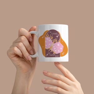 May include: White ceramic mug with a pink and orange design. The design features two dice with hearts on them, flames, and the text "I'm lucky to have you".