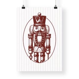 May include: A poster featuring a detailed illustration of a traditional nutcracker soldier in a maroon color. The nutcracker is inside an oval frame, set against a background of vertical pink stripes. The nutcracker has a crown, mustache, and a uniform.