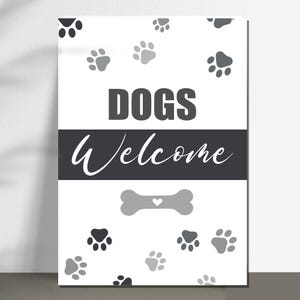 May include: A white sign with the words "DOGS Welcome" in black and white. The sign features paw prints and a bone graphic. The design is simple and suitable for a pet-friendly environment.