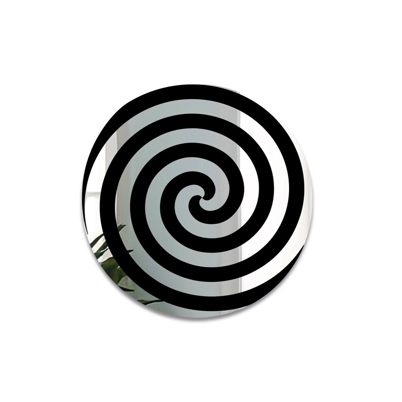 May include: A round mirror with a black and white spiral design. The mirror is reflective and shows a blurry image of a plant in the background.