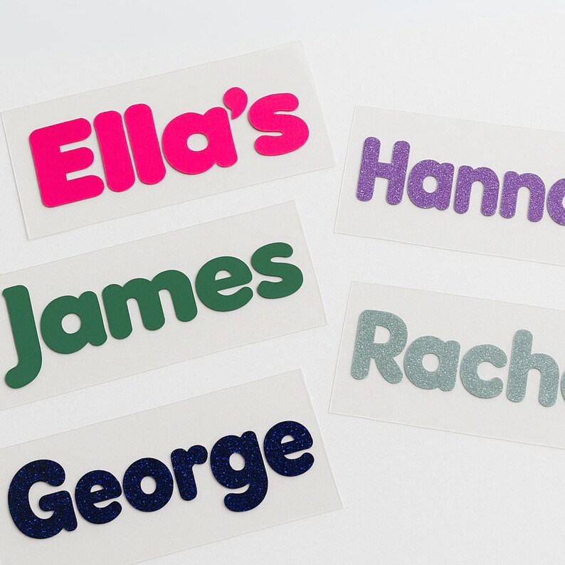 May include: Five personalized name labels with different colors and fonts. The names are Ella's, Hanna, James, Rachel, and George.