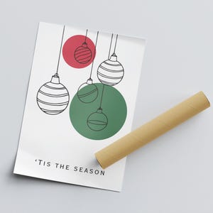 K&ouml;nnte beinhalten: Ein wei&szlig;er druckbarer Poster mit einem gr&uuml;nen Kreis und einem roten Kreis mit schwarzen und wei&szlig;en Ornamenten, die von oben h&auml;ngen. Der Text 'Tis the Season befindet sich am unteren Rand des Posters.