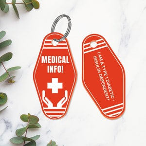 Pode incluir: Dois chaveiros de motel vermelhos com texto branco e listras. Um chaveiro diz "MEDICAL INFO!" com uma cruz branca e m&atilde;os. O outro chaveiro diz "I AM A TYPE 1 DIABETIC - INSULIN DEPENDENT!"