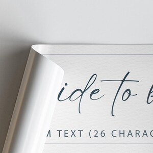 May include: A white poster with the words "ide to" in a dark blue script font. The corner of the poster is peeled back, revealing a white surface. The text "A TEXT (26 CHARAC" is visible.