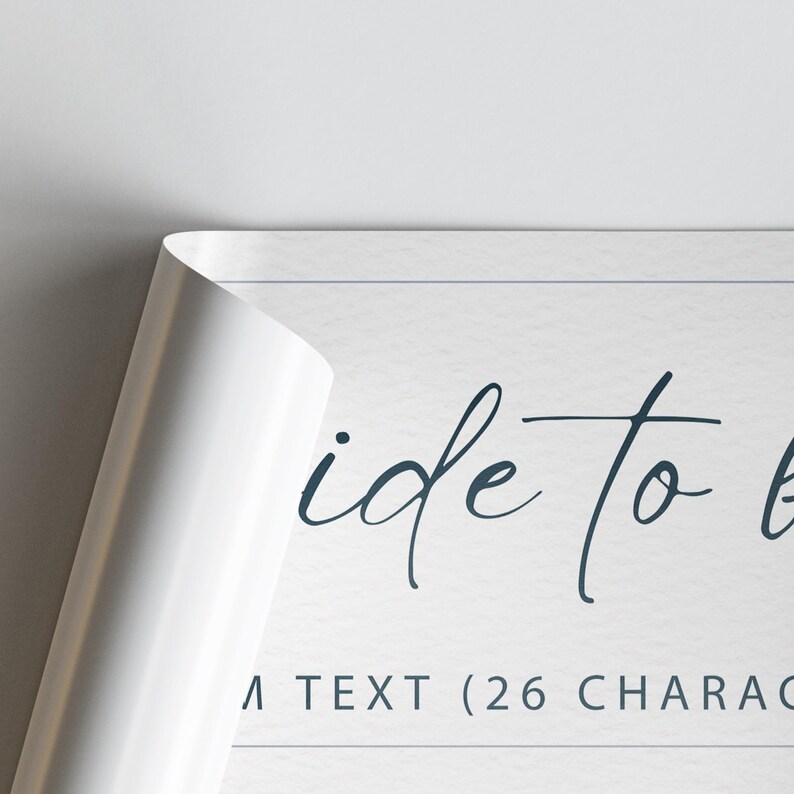 May include: A white poster with the words "ide to" in a dark blue script font. The corner of the poster is peeled back, revealing a white surface. The text "A TEXT (26 CHARAC" is visible.