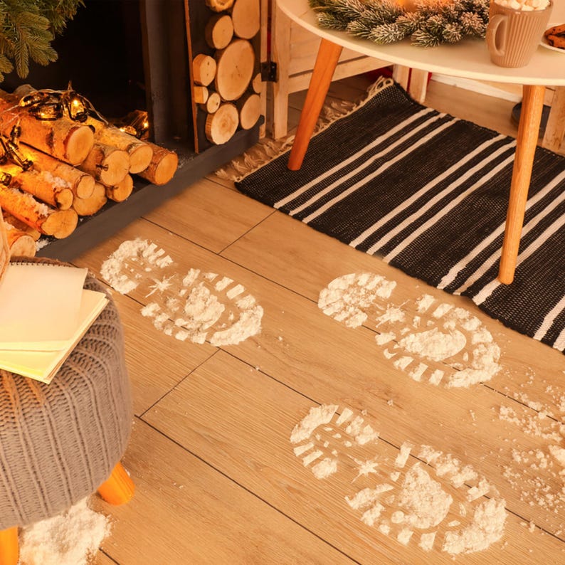 May include: Footprints made of white powder on a light brown wooden floor. The footprints lead towards a fireplace with stacked logs and a small table with a rug. A cozy winter scene.