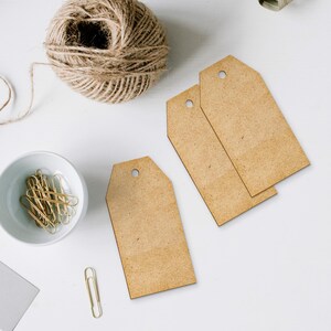 May include: Three brown paper gift tags with a hole punched in the top corner. The tags are on a white surface.