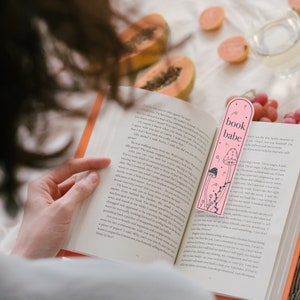May include: A pink bookmark with a mushroom design and the text "book babe".