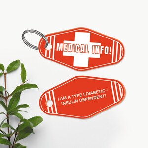 K&ouml;nnte beinhalten: Zwei rote Schl&uuml;sselanh&auml;nger in Form von Motelzimmerschl&uuml;sseln. Der obere Schl&uuml;sselanh&auml;nger hat ein wei&szlig;es Kreuz und den Text "MEDICAL INFO!" Der untere Schl&uuml;sselanh&auml;nger hat den Text "I AM A TYPE 1 DIABETIC - INSULIN DEPENDENT!"