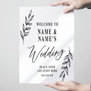 Pode incluir: Um cartaz de casamento branco com texto preto e detalhes florais. O cartaz diz "Bem-vindos ao casamento de NAME & NAME'S. Coloque sua localiza&ccedil;&atilde;o aqui 00100100".
