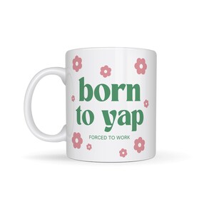 May include: White ceramic mug with a green design that says "born to yap" and "forced to work" in smaller text. The mug is decorated with pink flowers.