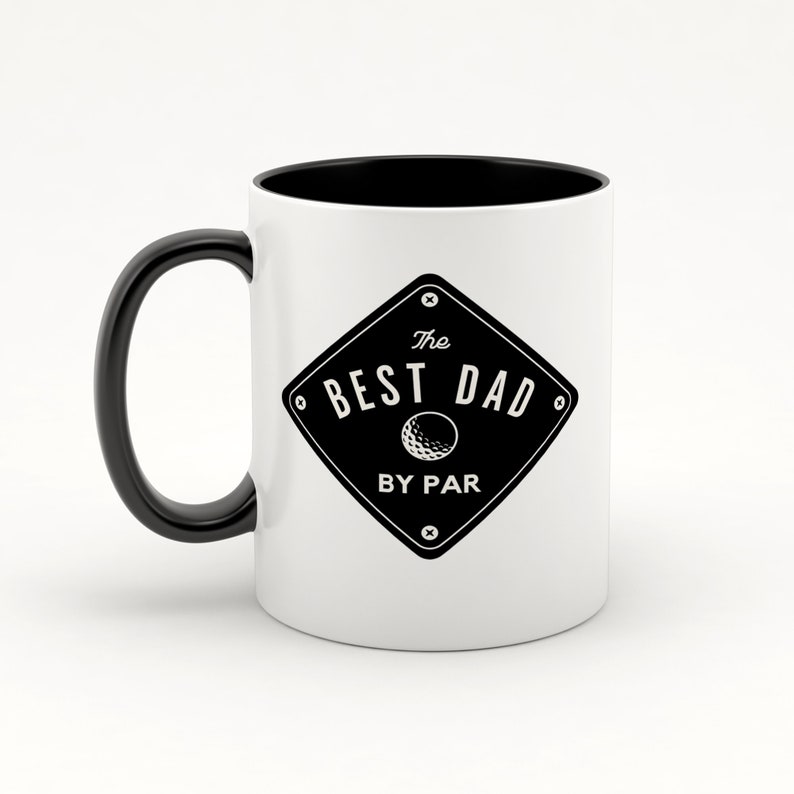 May include: White ceramic coffee mug with a black handle and black rim. The mug has a black and white graphic of a golf ball and the text "The Best Dad By Par".