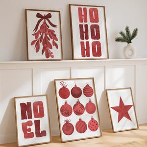 Puede incluir: Una colecci&oacute;n de l&aacute;minas art&iacute;sticas navide&ntilde;as enmarcadas. Las l&aacute;minas presentan dise&ntilde;os festivos en rojo, incluyendo mu&eacute;rdago, las palabras "HO HO HO", adornos navide&ntilde;os, las palabras "NOEL" y una estrella. Los marcos son de color marr&oacute;n c&aacute;lido.