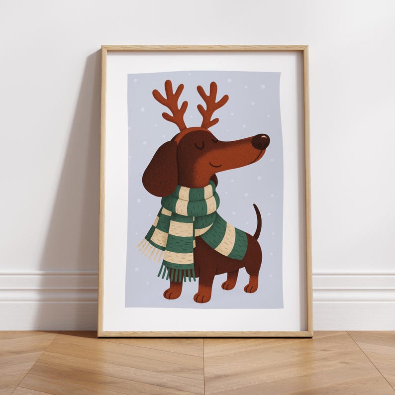 May include: A framed print featuring a cartoon dachshund wearing a green and white scarf and reindeer antlers. The dog is brown with a long snout and a happy expression. The background is a light blue with white dots.
