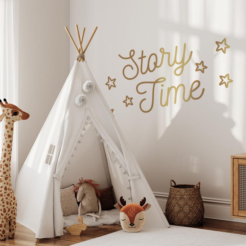 May include: A white teepee tent with a white pom-pom trim and a deer pillow inside. The teepee is set up in a room with a white wall that has gold star and "Story Time" decals.