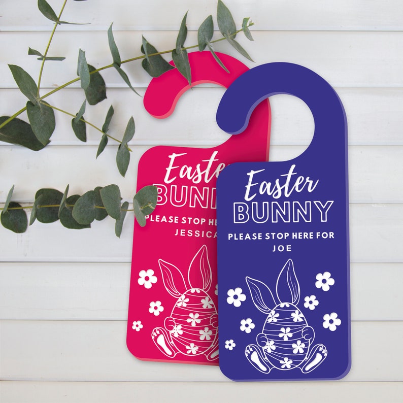 May include: Two door hangers, one fuchsia and one blue, with a curved top for hanging. Each features the text "Easter BUNNY" and a bunny illustration with floral accents. The fuchsia hanger says "Please stop here for Jessica", and the blue one says "Please stop here for Joe".